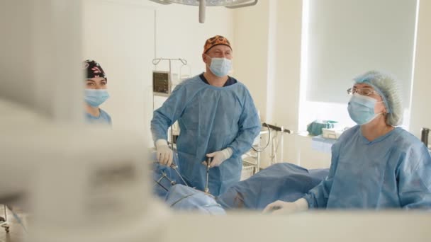외과 팀은 병원 수술실에서 자궁 제거 수술을 준비하고 있고, 외과 복강경 수술을 하고 있는 남성 외과의사도 있다. 부인 과 의사. — 비디오