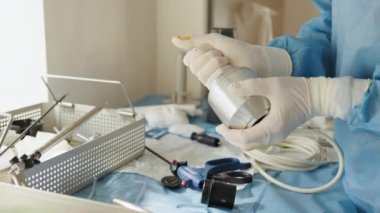 Laparoskopi prosedürü için trokar tutan steril eldivenli kadın ellerini kapatın. Laparoskopik makas ve kavrayıcılar mavi masada. Çok fonksiyonlu Laparoskopik Araçlar.