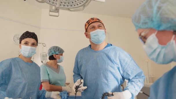 Profesyonel Cerrahlar Ekibi Hastane Ameliyathanesinde İstilacı Ameliyat Yapıyor. Cerrah Kullanımı ve diğer araçlar, anestezi uzmanı hayati değerleri izliyor. Ekip cerrahı çalışıyor.. — Stok video