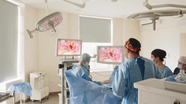 Лапароскопічний хірург дивиться на монітор під час лапароскопічної хірургії. Процес операції на гінекологічній хірургії з використанням лапароскопічного обладнання. Група хірургів в операційній кімнаті з хірургічним обладнанням — стокове відео