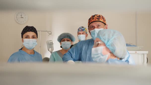 Equipe de chirurgiens opérant à l'hôpital. Chirurgien professionnel de la santé dans un bloc opératoire d'hôpital portant une casquette et un masque chirurgicaux. Femme médecin en uniforme médical mettant. — Video