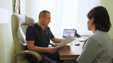 Yakışıklı doktor, klinikteki hastaya danışmanlık konusunda tavsiye veriyor. Sağlık konsepti. Hastanedeki hastayla randevusu olan bir doktor. Tıp bürosundaki uzmanlara danışmanlık yapan hastalar