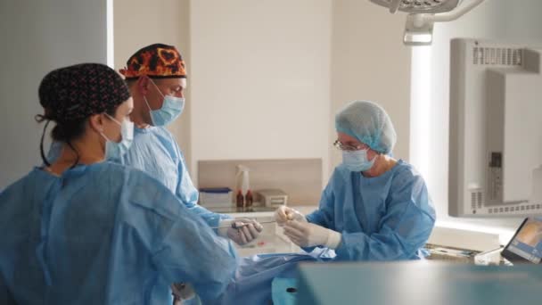 Il chirurgo utilizza un supporto per ago per tenere l'ago chirurgico e il filo per suturare la pelle dei pazienti. Un team di chirurghi cuce la pelle dei pazienti usando un porta aghi e una sutura chirurgica. — Video Stock