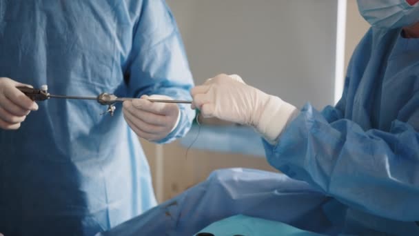 Cerrahlardan oluşan bir ekip, iğne tutacağı ve cerrahi dikiş atarak hastaların derisini dikiyor. Cerrah iğneyi ve ipliği tutarak hastanın derisini dikmek için iğne tutacağı kullanıyor.. — Stok video