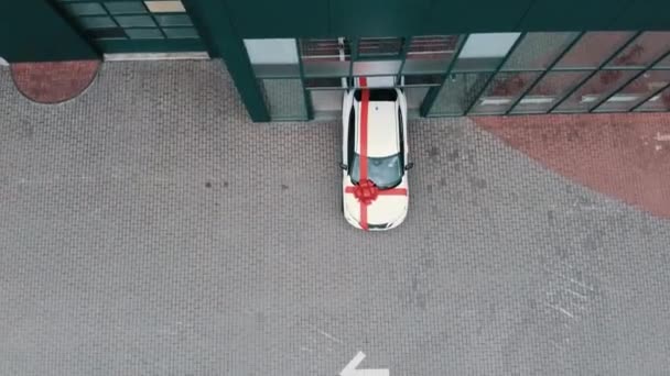 Nuova auto bianca di lusso con grande fiocco rosso cavalcando fuori dal moderno salone auto. Acquisto costoso di acquirente. Concetto di trasporto, sorpresa e vendita. Aereo. Traduzione: Parcheggio per i clienti — Video Stock