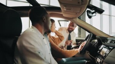 Araba galerisindeki çiftle konuşan pozitif ve arkadaş canlısı bir satıcı. Resmi kıyafet satıcısı pahalı alışverişler için çok ırklı çiftlere danışıyor. Kuaförden araba almak.