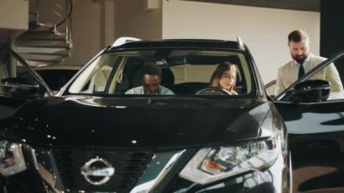 Modern otomobilin içinde oturan çift, yetkili bir galeri müdürüyle konuşuyor. Yeni araç seçiliyor. Pahalı satın alma kavramı. Otomobilde oturan farklı bir çift. Kuaförden araba almak.