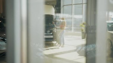 Bir çift arabanın yanında satıcıyla duruyor ve satın almadan önce tüm detayları inceliyor. İnsan konsepti, araba işi ve satış. Yeni araç seçiliyor. Modern bir mağazadan araba almak.