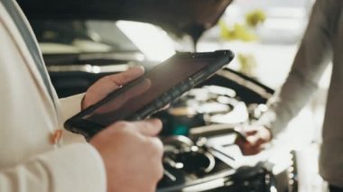 Yetenekli araba satıcısı müşterileriyle çalışmak için dijital tablet kullanıyor. Torbacı galeride dijital tablet kullanıyor. Ekran dijital tableti dokunuyor. Modern çalışma süreci.