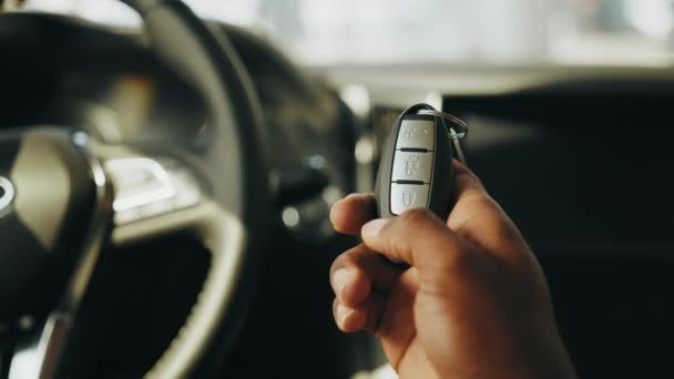 Primer plano del hombre sosteniendo la llave del coche sin contacto en la mano y terminando el botón costoso del coche. Arranca el botón del motor. Dedo pulse el botón para arrancar el motor del coche. Arrancar motor. — Vídeos de Stock