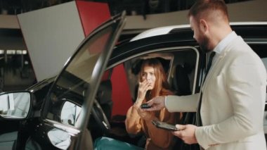 Satıcı yeni otomobilin anahtarlarını veriyor. Modern otomotiv içinde oturan mutlu çoklu etnik çift yetkili bir bayilik müdürüyle konuşuyor. Yeni araç seçiliyor. Pahalı satın alma kavramı.