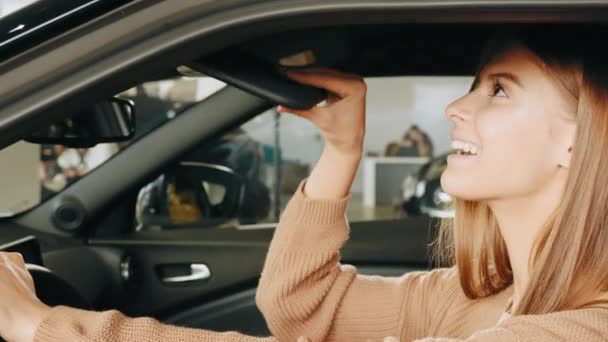 Hezká mladá dáma zkoumá interiér luxusního auta, zatímco sedí uvnitř. Běloška žena testuje auto před nákupem. Koncept lidí a dopravy. Mladá žena kupuje nové auto. — Stock video