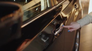 Sürücü parmak iziyle arabayı açmak ya da kapatmak için parmak izini kulpuna koyarak anahtarsız giriş kullanıyor. Kablosuz akıllı anahtar kullanan bir kadın arabanın kapısını açıyor ve içeri giriyor..