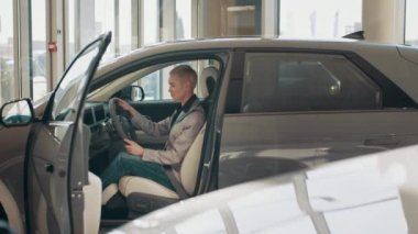 Eko araba satışı konsepti. Otomatik sürüş sistemi olan yeni nesil elektrikli aracın test sürüşü. Çekici beyaz kadın yeni modern arabanın direksiyonunda oturuyor. Eko araba satışı kavramı
