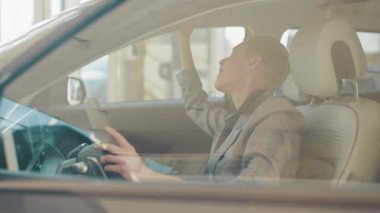 Beyaz kadın müşteri satın almadan önce otomatik test yapıyor. Bayan içeride otururken lüks arabanın içini inceliyor. Otomatik sürüş sistemi olan yeni nesil elektrikli aracın test sürüşü.