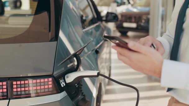 Unrecognizable businessman plugging electric car from charging station. Senior is plugging in power cord to an electric car. Businessman charging electric car at charging station. Process charging — Stock Video