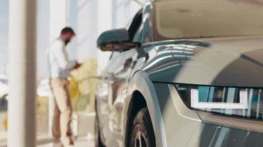 Eko araba konsepti. Arka planda erkek silueti olan elektrikli bir arabanın yakınında. Garajda şarj olurken jenerik elektrikli cip. Evde şarj edilen bir adam ya da ofiste modern bir park yeri