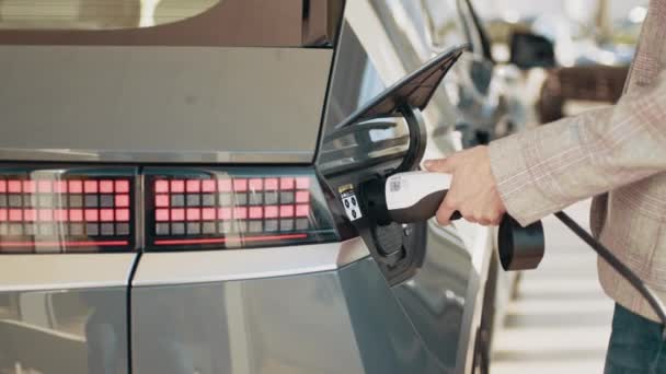 Close-up van vrouwelijke handen met behulp van afstandsbediening om de moderne elektrische auto op te laden. Slim ecologisch leven. Vrouw met oplaadkabel voor elektrische auto, wachtende elektrische auto op te laden. — Stockvideo