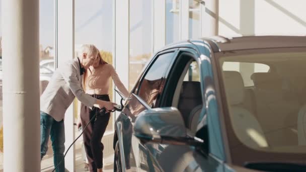 Concept de voiture électrique écologique. Une vie écologique intelligente. Deux femmes donnant cinq tout en chargeant une nouvelle voiture électrique moderne chez le concessionnaire de véhicules. Technologie de voiture électrique écologique. Chargement voiture électrique — Video