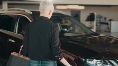Siyah tişörtlü, mutlu, gülümseyen kadın müşteri müşterisi araba seçiyor araba galerisi galerisi galerisi galerisi galerisi galerisi araba galerisi kapalı motor fuarında araba almak istiyor. Satış konsepti.