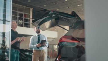 Güzel bir bayan müşteri ve galeride arabayı inceleyen bir satıcı. Erkek kadına bagajın nasıl kapatılacağını öğretiyor. Satıcıyla birlikte iş kadını yeni bir arabanın bagajını inceliyor..