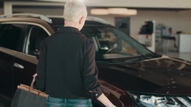 Gelukkig glimlachende vrouw klant vrouwelijke koper klant in zwart shirt op zoek in spiegel auto kiezen auto wilt kopen auto in de auto showroom auto salon dealer winkel motorshow indoor. Verkoopconcept. — Stockvideo