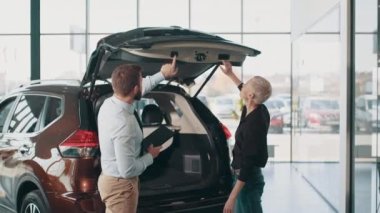 Güzel bir bayan müşteri ve galeride arabayı inceleyen bir satıcı. Erkek kadına bagajın nasıl kapatılacağını öğretiyor. Satıcıyla birlikte iş kadını yeni bir arabanın bagajını inceliyor..