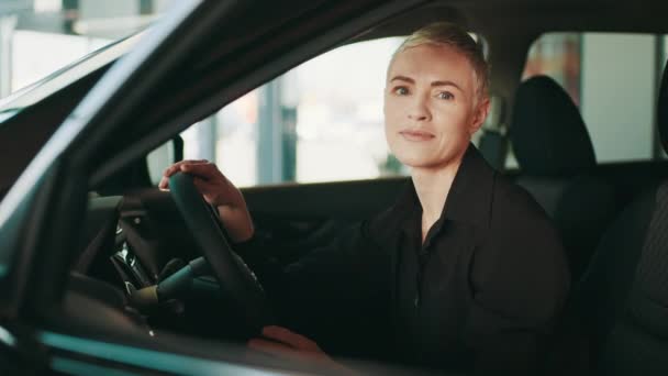 Pojęcie ludzi i transportu. Biała kobieta testuje auto przed dokonaniem zakupu. Pojęcie ludzi i transportu. Pani bada wnętrze luksusowego samochodu siedząc w środku. — Wideo stockowe