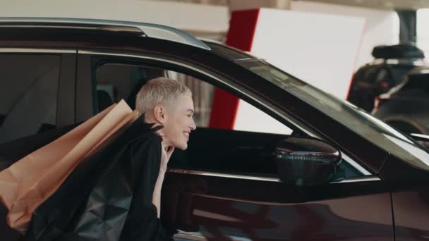 Šťastná usměvavá žena zákazník žena kupující klient v černé košili při pohledu v zrcadle auto vybrat auto chtějí koupit automobil v autosalonu prodejna prodejna autosalonu obchod uvnitř. Koncept prodeje. — Stock video