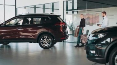 Bagajı ellerim olmadan açıyorum. Temassız bagaj açma sistemi sensörlerle çalışıyor. Bir kadın bagajı açar ve paketleri arabaya koyar. Yeni araba fonksiyonlarının gösterimi