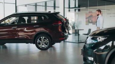 Bagajı ellerim olmadan açıyorum. Temassız bagaj açma sistemi sensörlerle çalışıyor. Adam bagajı açar ve paketleri arabaya koyar. Yeni araba fonksiyonlarının gösterimi