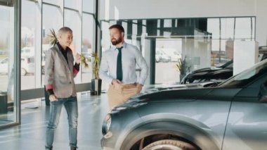 Araba satıcısı yepyeni bir araba gösteriyor ve araba galerisinde ya da galeride performanslarından bahsediyor. Satıcı, arabanın anahtarını bir müşteriye veriyor. Yeni araba alan bir kadın. Yeni otomatik alınıyor