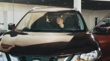 Araba galerisindeki kadın. Arabayı alan kadın. Arabada oturan şık bir kız arabanın içini inceliyor. - Ne? Kadın mutlu, gülümsüyor ve yeni bir araba almaktan zevk alıyor. Bir araba al.