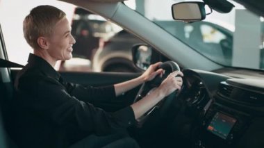 Arabada oturan şık bir kız arabanın içini inceliyor. - Ne? Kadın mutlu, gülümsüyor ve yeni bir araba almaktan zevk alıyor. Yeni bir araca saygı duyan bir kız. Alıcı bir araba seçer.