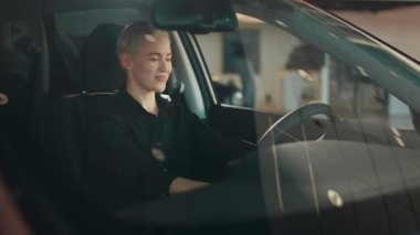 Bir araba galerisinde yeni bir lüks elektrikli araba kullanan mutlu genç bir kadının portresi. Kız yeni arabasını sürerken mutluluk duygularını gösteriyor. Alıcı bir araba seçer.