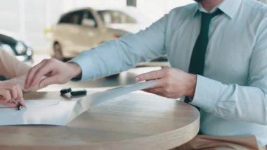 Kapanış sözleşmesi ya da satış elemanı tarafından temsil edilen yeni kredi kartı sözleşmesi. Araba için sözleşme. Satış mağazasında satıcıyla kağıt imzalayan bir müşteri. Araba galerisini ziyaret ediyorum.