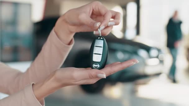 Έμπορος αυτοκινήτων δίνει τα κλειδιά σε έναν πελάτη κατά των αυτοκινήτων που σταθμεύουν. Επιδεικνύοντας κλειδιά στην έκθεση. Νέα κλειδιά αυτοκινήτων, αντιπροσωπεία και την έννοια των πωλήσεων. Έμπορος αυτοκινήτων με κλειδί. Αυτόματη και ενοικίαση φόντο έννοια. — Αρχείο Βίντεο