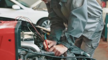 Araba tamiri servisinde çalışan profesyonel bir tamirci. Otomobil teşhisi. Araç tamircisi, araç hizmet atölyesindeki teşhis ekipmanlarında motor arızası arıyor