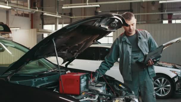 Using Digital Tablet For Car Diagnostic. mechanic using a tablet pc at the repair garage service. Interactive Diagnostics Software on an Advanced Computer. Service maintenance of engine repair. — Video