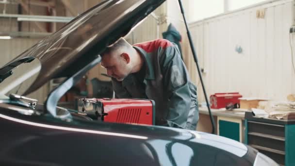 Car mechanic in a workshop engine repair and diagnosis on a vehicle. Professional car mechanic working in auto repair service. Automobile diagnosis. Car repair and maintenance. Performing diagnostics — 비디오