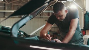 Tamirci elektrik tesisatını yeniliyor mu diye kontrol ediyor. Otomobil servisi atölyesi. Düzenli önleyici araba bakımı. Otomobil servisi, bakım konsepti. Elektrikçi bir araba motoruna sorun çıkarıyor.