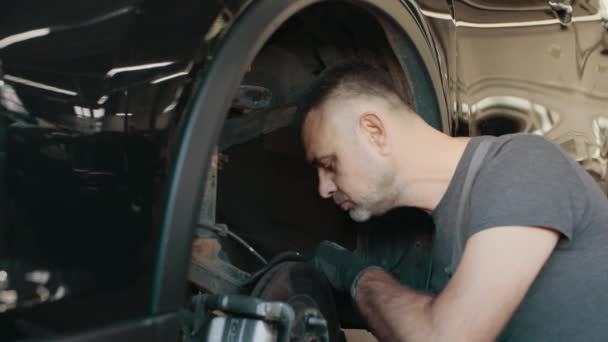 Mechanic looking at steering chassis under a car. Garage service. Automobile diagnostic. Auto repair concept. Car service, maintenance and people concept - auto mechanic man working at workshop — Stock Video