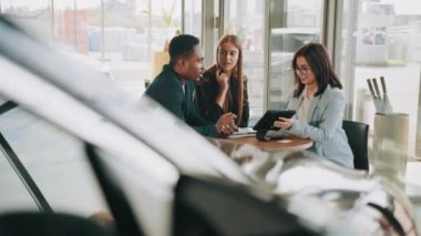 Neşeli, çok kültürlü bir çift modern kuaförde satış elemanı ile oturuyor. Araba satın alma konusunda başarılı bir anlaşma. Otomobil işi konsepti. Galerideki alıcılarla çalışırken dijital tablet kullanan yönetici.