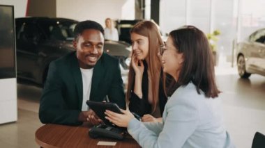 Oto kuaförde çok ırklı bir çiftle oturan yetkili bir araba satıcısı ve yeni bir araç almak için bağlantı kuruyor. Kadın satıcı araba alımı konusunda çeşitli çiftlere danışıyor.