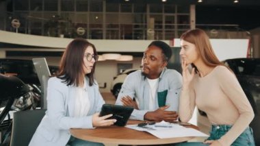 Çift dijital tablette araba satın alma emrini imzalıyor. Oto kuaförde çok ırklı bir çiftle oturan yetkili bir araba satıcısı ve yeni bir araç almak için bağlantı kuruyor. Kadın satıcı