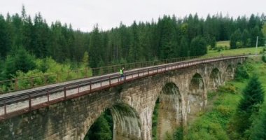 Demiryollarında havadan ateş edilmiş inşaat işçisi. Demiryolunda çalış. Nehir üzerindeki eski demiryolu köprüsü. Demiryolu mühendisi. Demiryollarında yürüyen ve rayları kontrol eden mühendis. İnsanlar demiryolunda yürür.