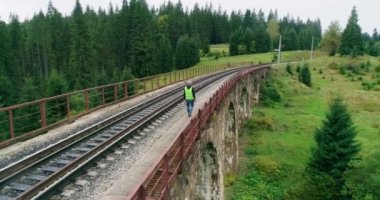 Demiryollarında havadan ateş edilmiş inşaat işçisi. Portre mühendisi teftiş altında ve inşaat işlemleri demiryolu şalterini kontrol ediyor. Güvenlik üniforması ve güvenlik kaskı takan mühendis..