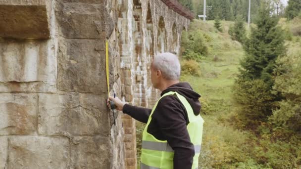 Inspect and checking concept. Senior male engineer to restore ancient buildings or bridges. Reconstruction of bridges, preservation of ancient railway bridges. Engineer-inspector at work. — Vídeos de Stock