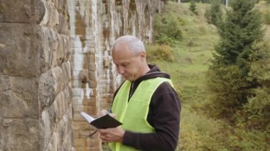 Eski binaları ve köprüleri restore etmek için kıdemli erkek mühendis. Köprülerin yeniden inşası, antik demiryolu köprülerinin korunması. Mühendis müfettişi iş başında. Konsepti incele ve kontrol et.