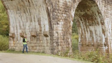 Eski binaları ve köprüleri restore etmek için kıdemli erkek mühendis. Mühendis veriyi dizüstü bilgisayara yazar. Köprülerin yeniden inşası, antik demiryolu köprülerinin korunması. Mühendis müfettişi iş başında.